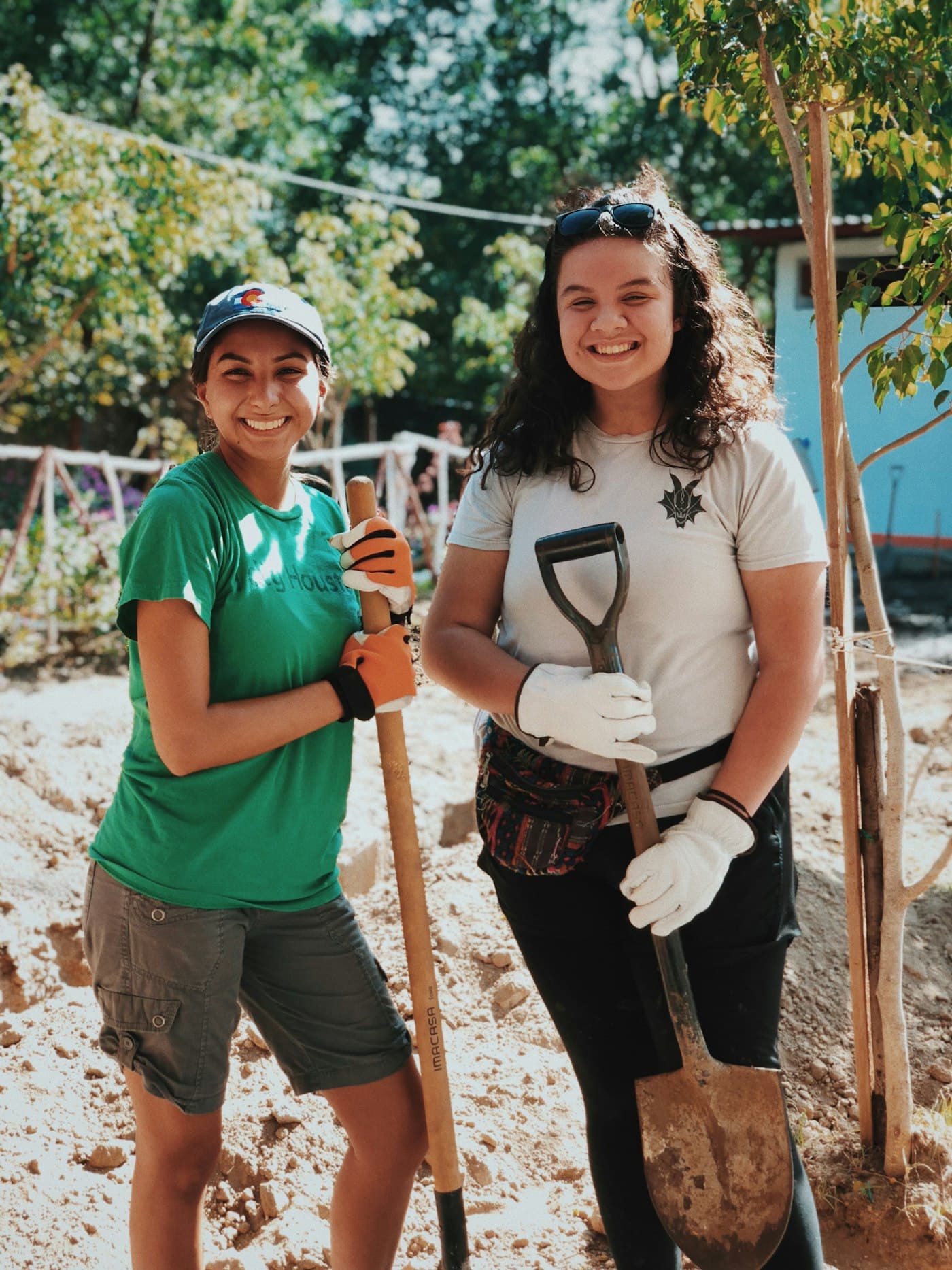 Dos voluntarias sonriendo mientras plantan un árbol en una jornada comunitaria